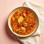 A bowl of jambalaya with meat and vegetables, a hearty and healthy meal idea from a wellness coach.