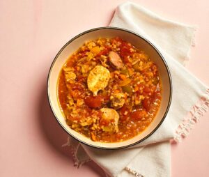 A bowl of jambalaya with meat and vegetables, a hearty and healthy meal idea from a wellness coach.