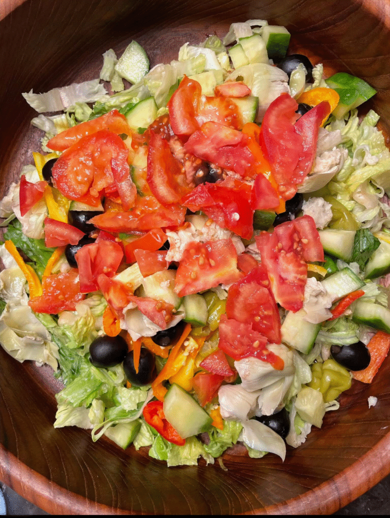 A large dinner salad with olives and tomatoes, a whole-food meal idea from nutritional coaching.