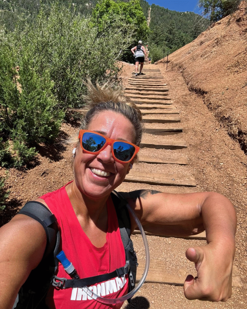 Crystal Billings, a wellness coach, smiling with orange sunglasses after a challenging outdoor workout, promoting active and sustainable wellness.