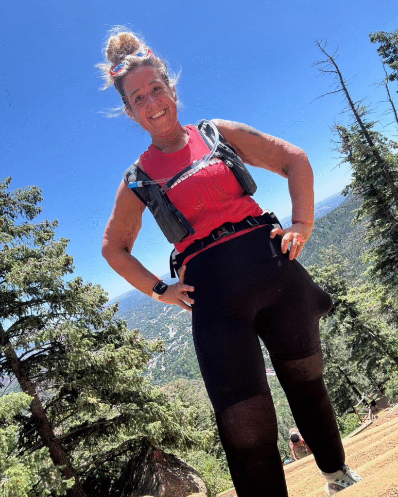 Crystal Billings looking down at the camera, after a trail run, embodying an energetic wellness coach focused on holistic health in nature.