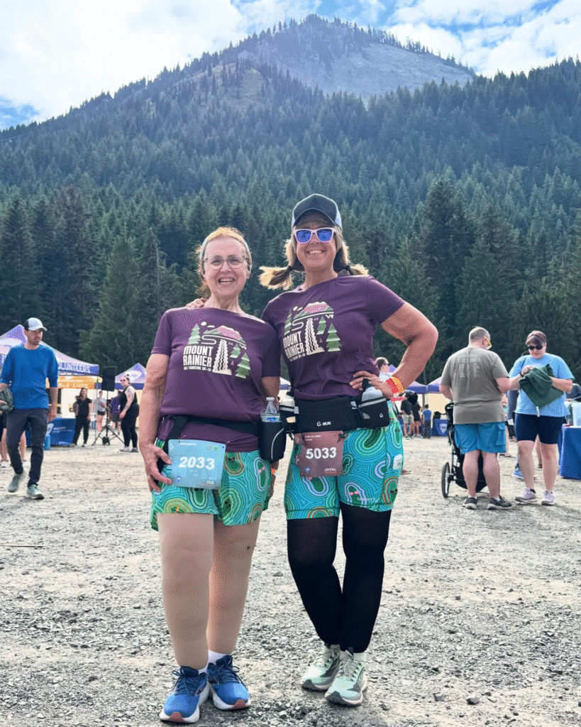 Crystal Billings and a friend at a "Run the PNW" race, demonstrating an active lifestyle through wellness coaching and health coaching.