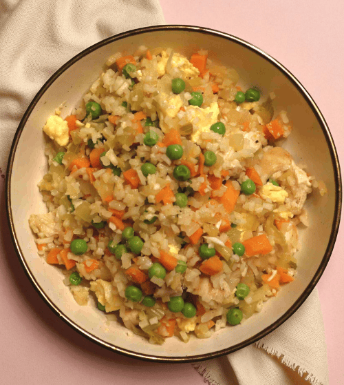 A bowl of chicken and cauliflower fried rice, a low-carb and healthy recipe from a nutritional coaching plan.